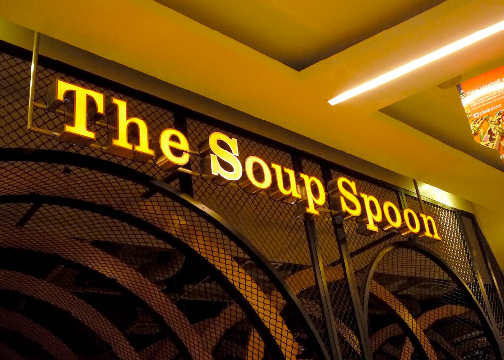 Illuminated The Soup Spoon lettering following a curved shopfront